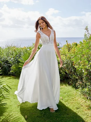 Braut bewegt ein fließendes Brautkleid in einer Gartenkulisse