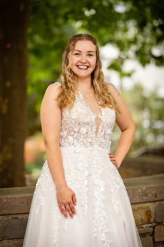 Braut in einem Spitzenkleid zwischen grünen Bäumen