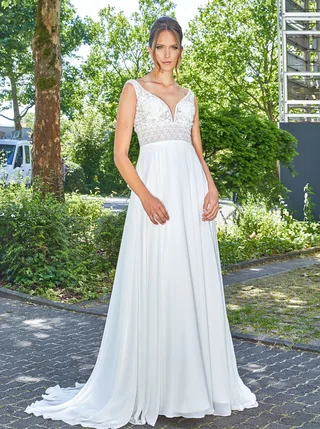 Braut in einem schlichten Kleid mit klarer Silhouette im Grünen