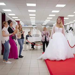 Braut geht im Traumkleid über den roten Catwalk